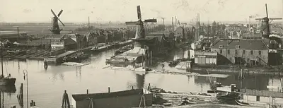 Delfshaven 1910,  Overzicht van de Middenkous met links de Voorhaven en molen Het Vertrouwen, in het midden molen De Distilleerketel, met daar achter de wiek van de molen De Graankorrel, en rechts de Achterhaven met molen De Waakzaamheid., Stadsarchief Rotterdam (Public Domain Mark 1.0)