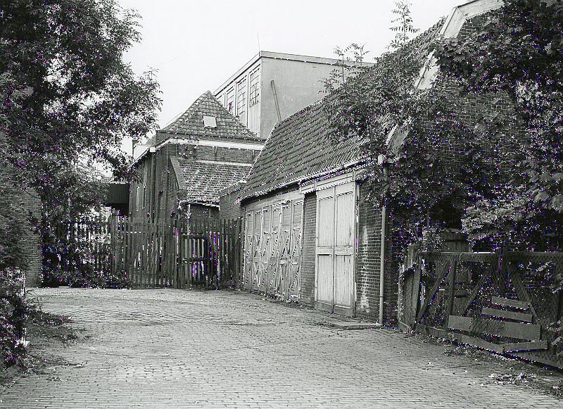 1, Molen 16646 Grutterij van Hendrik de Vos (Geervliet), Foto collectie van het Streekarchief Voorne-Putten. De fabrieksgebouwen van de grutterij en spliterwtenfabriek van de firma Trouw. De betonnen hoogbouw stamt uit 1924 en de bakstenen gebouwen uit 1936. Hierin werden vuren gestookt om erwten en bonen te drogen. In 1984 is het complex gesloopt. | Database Nederlandse molens