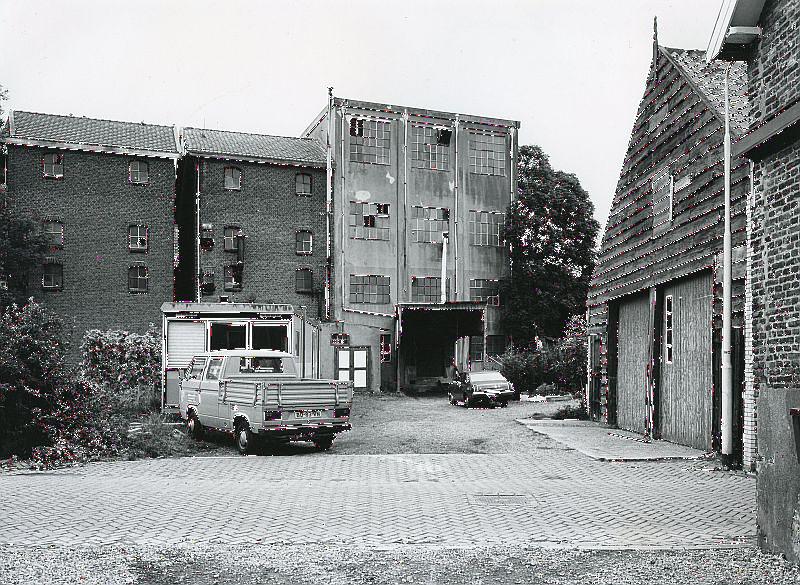 2, Molen 16646 Grutterij van Hendrik de Vos (Geervliet), Foto collectie van het Streekarchief Voorne-Putten. De fabrieksgebouwen van de grutterij en spliterwtenfabriek van de firma Trouw. De betonnen hoogbouw stamt uit 1924 en de bakstenen gebouwen uit 1936. Hierin werden vuren gestookt om erwten en bonen te drogen. In 1984 is het complex gesloopt. | Database Nederlandse molens
