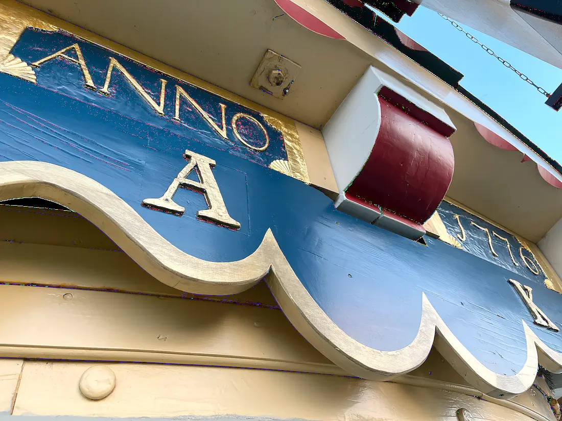 7, Molen 01922 De Vier Winden (Rotterdam), William Bouter (01-04-2026)&nbsp;Een close-up van de herstelde baard. Bij de restauratie kwamen sporen van dit fraaie diep donkerblauw en bladgoud naar boven. Een restant uit een periode waar blauw een algemenere kleur was op molens dan nu. Er is toen besloten dit te herstellen. | Database Nederlandse molens