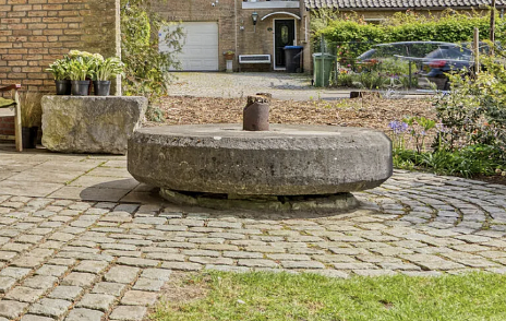1, Molen 01996 De Oude Molen / Molen van Smoor / Molen van Van Meel (Oud Gastel), in de tuin van de woning op de voormalige molenplaats ligt een molensteen, de steen lijkt op een steen van een kollergang | Database Nederlandse molens