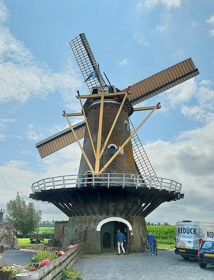 4, Molen 01865 De Oude Molen (Fijnaart), Jesse Bergquist (28-7-2021)De situatie één jaar later: het molenerf van de Oude Molen is drastisch en onherstelbaar veranderd. Als eerste verdween de oude opslagschuur aan de noordoost kant van de molen wegens zware bouwvalligheid. Een paar maanden later verdween het oude bakkerij gebouw wat tegen de molen aan stond aan de zuidwest zijde. Dit laatste gebeurde eigenlijk om dezelfde reden als de andere schuur. Het enige verschil is, dat de stelling deels op het dak van het bakkerijgebouw rustte. Toen een deel van het dak van het bakkerij gebouw naar beneden kwam, is ervoor gekozen om het gebouw, wat ook aan het verzakken was, te slopen en aan deze kant de stelling ook weer van schoren te voorzien.  | Database Nederlandse molens media-bestand